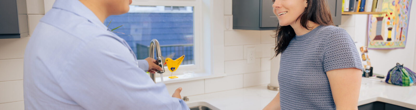 Tacoma plumber running water to test a kitchen faucet while talking with a homeowner about the repair