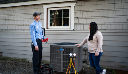 Pacific Heating and Cooling male technician speaking with female homeowner about her heat pump service, tune-up and installation