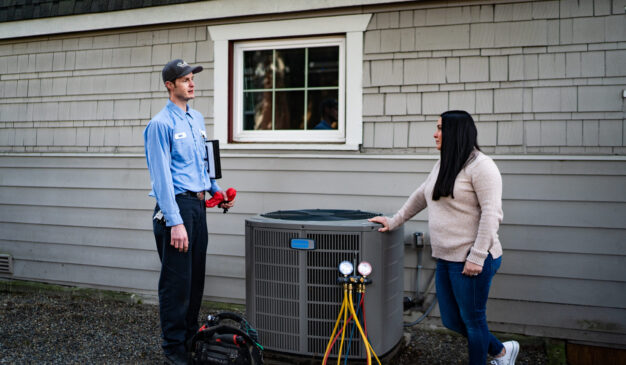 Pacific Heating and Cooling male technician speaking with female homeowner about her heat pump service, tune-up and installation