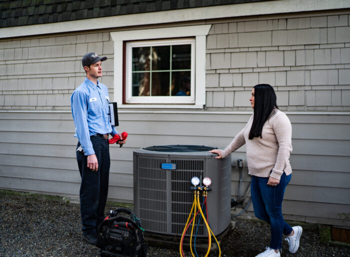 Pacific Heating and Cooling male technician speaking with female homeowner about her heat pump service, tune-up and installation
