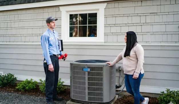 HVAC technician discussing a heat pump installation with a Tacoma homeowner outside their home.