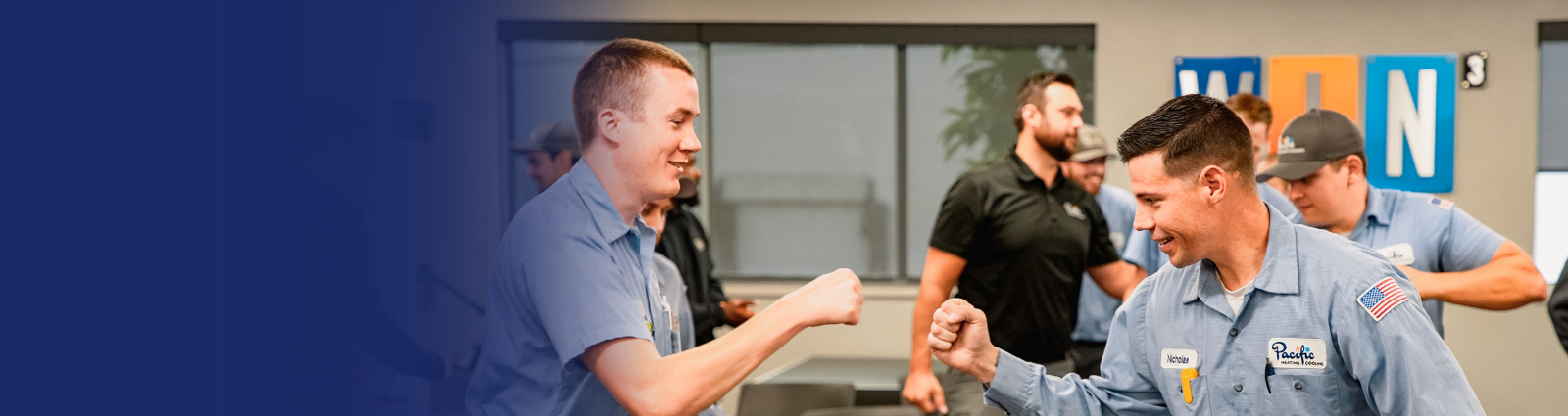 HVAC team members sharing a congratulatory fist bump during a team meeting