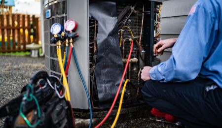HVAC technician testing a heat pump outdoor unit during a service visit