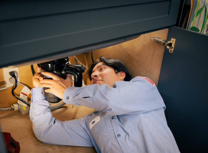 Tacoma plumber lying under a kitchen sink working on a garbage disposal and P-trap drain connection