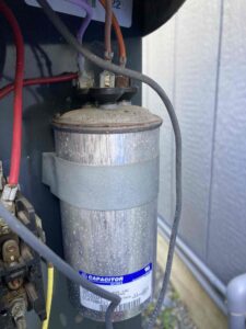 Dual run capacitor inside an outdoor AC unit in Tacoma showing weathering and age