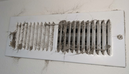 Dusty wall air vent with lint buildup, a sign of poor indoor air quality
