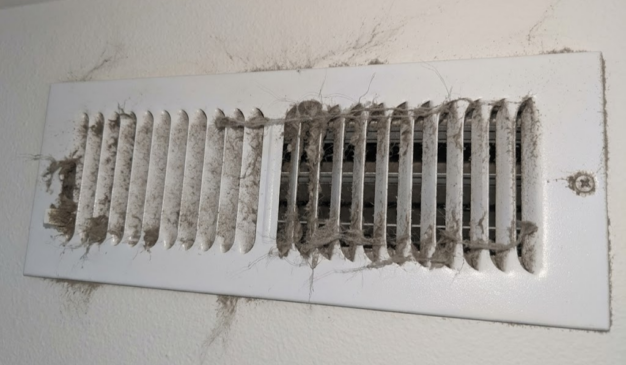 Dusty wall air vent with lint buildup, a sign of poor indoor air quality