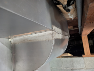 Leaking crawlspace air duct with torn insulation pulling unfiltered air into a homeTitle: Leaky crawlspace ductwork with damaged insulation Caption: A crawlspace duct with a gapping seam and torn insulation, a common source of unfiltered, dusty air.