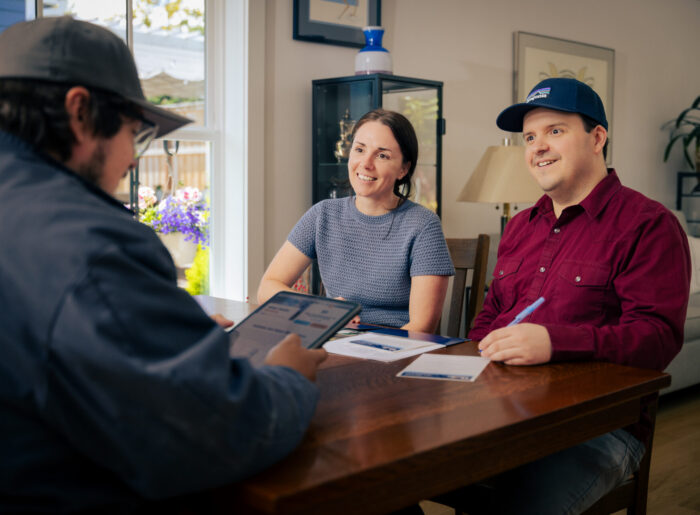 Tacoma plumber sitting at a dining table showing a tablet to a couple while discussing plumbing service options