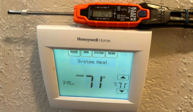 Technician checking thermostat accuracy with a probe thermometer during a no heat repair call