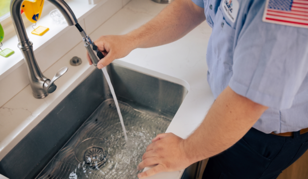 Pacific Heating & Cooling plumber checking a kitchen sink drain