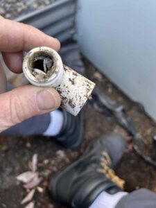 Clogged condensate drain line causing a musty smell from vents Caption: A blocked condensate line like this is one of the most common reasons water backs up into the system and a musty smell follows.