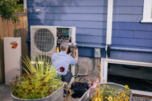 Pacific Heating and Cooling technician servicing an outdoor heat pump unit