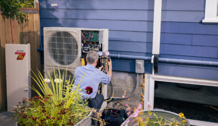 Pacific Heating and Cooling technician servicing an outdoor heat pump unit