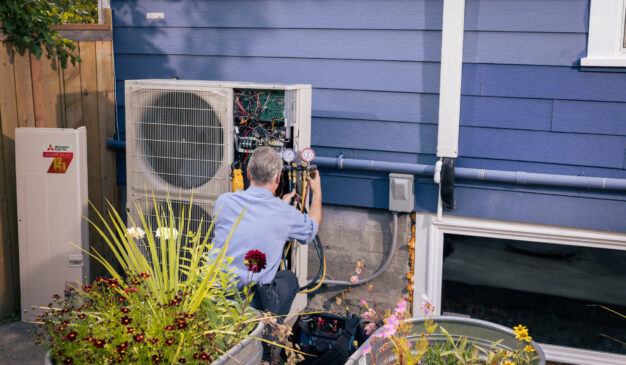 Pacific Heating and Cooling technician servicing an outdoor heat pump unit