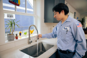Pacific plumber checking a kitchen faucet to decide on repair vs. replace