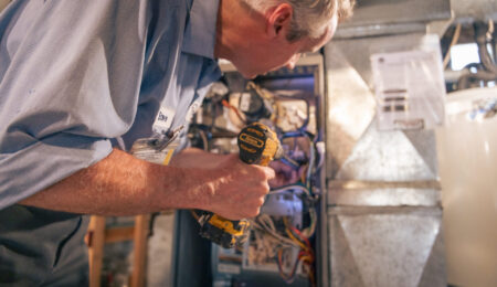 Technician inspecting furnace electrical panel and wiring during a noise diagnostic call.