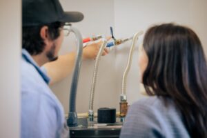 Technician pointing out the water heater shutoff valve to a homeowner