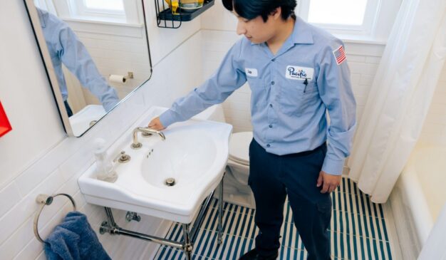 Plumber running a bathroom faucet to check for drips and supply line leaks during a water leak inspection